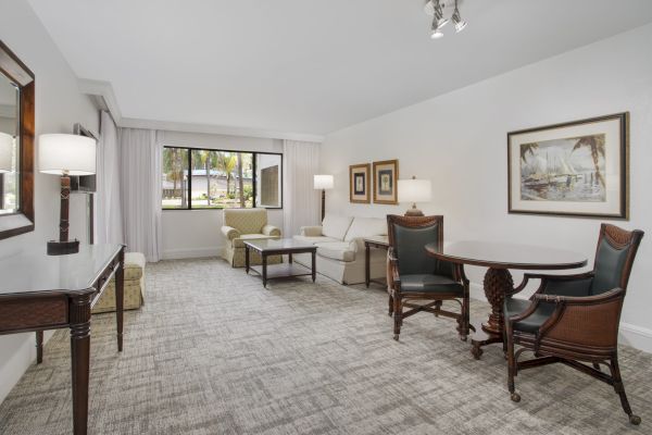 An elegant living room with sofas, chairs, a dining area, artwork, and a view to the outside.