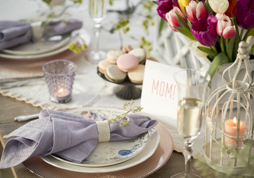 A beautifully set table with purple napkins, flowers, macarons, a 