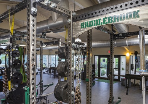 The image shows a well-equipped gym with various weightlifting and fitness equipment and the sign 